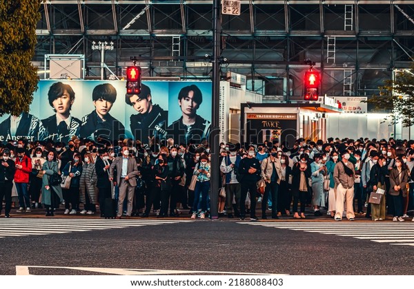 Tokyo,\
Japan - 04.2022: Crowd of Japanese commuters waiting to cross\
street in Shibuya City at the scramble crossing upon pedestrian\
traffic light turn green during evening rush\
hour