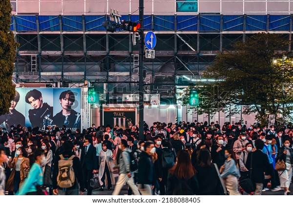 Tokyo,\
Japan - 04.2022: Crowd of Japanese commuters waiting to cross\
street in Shibuya City at the scramble crossing upon pedestrian\
traffic light turn green during evening rush\
hour