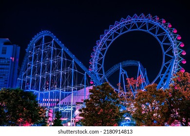 Tokyo, Japan - 05.2022: Abstract Cyberpunk Amusement Park With Neon Lights Illumination. Tokyo Dome City Attractions Amusement Park With Ferris Wheel And Roller Coaster At Night. Futuristic Metaverse