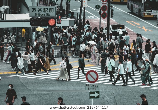 Tokyo, Japan - 06.2022: Crowded\
Shibuya Scramble Crossing at rush hour with people, worker, and\
tourist crossing the crosswalk in hurry to catch commute\
train
