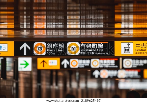 Tokyo, Japan - 06.2022: Japanese neon direction\
sign in metro station showing direction to mass transit like train\
and metro train.