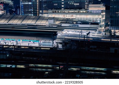 Tokyo, Japan - 10.2022: Train Platforms At Tokyo Station At Night With Illumination From Office Tower In Background