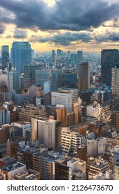 Tokyo, Japan - April 09 2021: Bird's-eye View Of The Hamamatsucho District With The Metropolitan Expressway Inner Circular Route Passing Through Buildings And Skyscrapers At Sunset Below A Cloudy Sky.