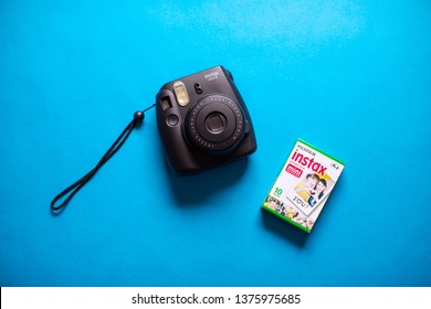 Tokyo, Japan, April 20, 2019:  Fujifilm instax black mini camera and instant film on blue background