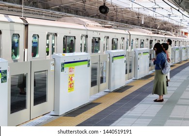 TOKYO, JAPAN - April 21, 2019: A Train Arriving At Funabori Stion In Front Of Platform Screen Doors. The Station Is Above Ground But Is Part Of The Tokyo's TOEI Subway System. Some Motion Blur.