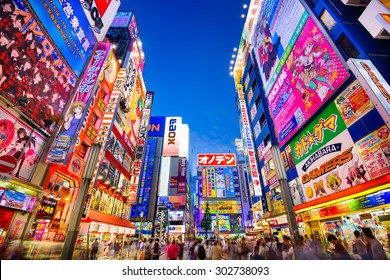 TOKYO, JAPAN - AUGUST 1, 2015: Crowds pass below colorful signs in Akihabara. The historic electronics district has evolved into a shopping area for video games, anime, manga, and computer goods.
