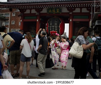 Tokyo, Japan - august 22 2019: Wide shot of two japanese girls taking a selfie among the crowd at the Sensō-ji gates 