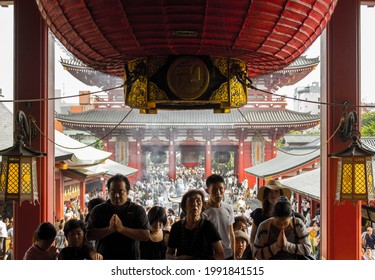 Tokyo, Japan - august 22 2019: Devote family praying at the Sensō-ji buddhist temple
