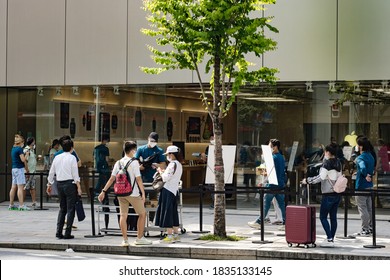 TOKYO, JAPAN - August 26, 2020: People Line Up Outside The Apple Store In Tokyo's Ginza Area. They Wear Face Masks & Practice Social Distancing During The Coronavirus Outbreak.