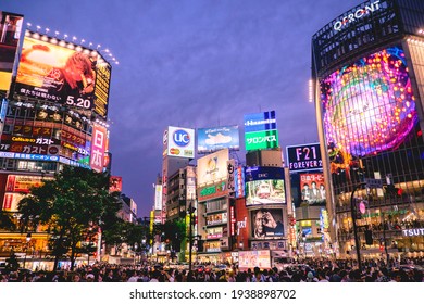 Tokyo, Japan - Circa 2015: Colorful panoramic view of the famous Shibuya crossing at Tokyo downtown with a crowd of people in the sunset and buildings full of advertising and screens