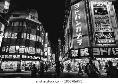 Tokyo, Japan - Circa 2015: People walking at the streets of Shinjuku, full of neon, advertisings, signs and colorful screens in the night (in black and white)