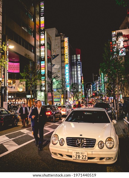 Tokyo, Japan - Circa 2016: People walking, colorful\
night lights, big car, buildings, restaurants and stores at\
Shinjuku in the night