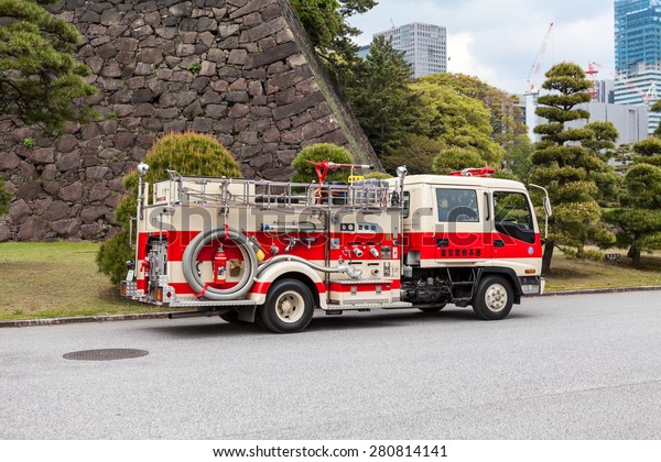 TOKYO, JAPAN - CIRCA APR, 2013: Japanese firetruck\
with firefighters drives in ground of the Tokyo Imperial Palace.\
The Tokyo Imperial Palace is the main residence of the Emperor of\
Japan