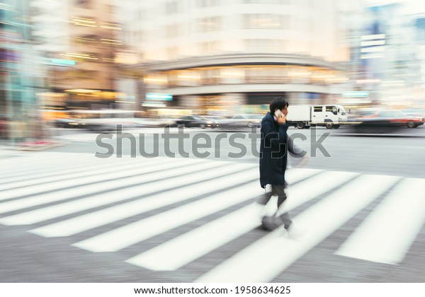 Tokyo, Japan - December 10, 2015: Japan, Tokyo, Japanese\
man talking on his phone  by passing  at the Ginza shopping\
district. 