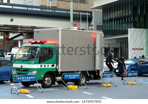 TOKYO, JAPAN - December 12, 2019: A police truck\
in Ginza involved in collecting cones & road signs after\
\'pedestrian paradise day\' when roads are closed to cars.  Building\
is Konami Creative\
Center.