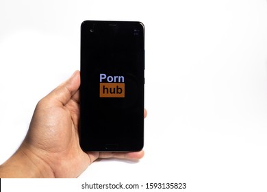 Tokyo, Japan - December 19, 2019 : Man holding smartphone with Pornhub logo on white background.