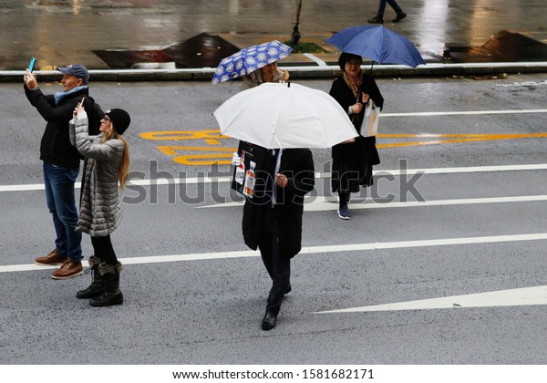 TOKYO, JAPAN - December 7, 2019: Overhead view of\
street in Ginza on a rainy day with people taking photos. It\'s a\
so-called \'pedestrian paradise day\' so the road is closed to cars.\
Some motion blur.