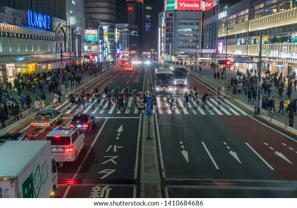 TOKYO, JAPAN - FEB 2019 : Crowd of undefined\
people walking on the street cross-walk with car traffic in\
Shinjuku on Febuary 16, 2019 in Tokyo, Japanese culture and\
shopping neon street\
concept