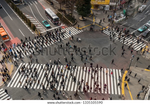 TOKYO, JAPAN - FEB 2019 : Undefined People and car\
Crowd with areial view pedestrains intersection cross-walk Shibuya\
crosswalk car traffic at afternoon time on Febuary 14, 2019 in\
Tokyo, Japan.