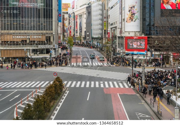 TOKYO, JAPAN - FEB 2019 : Undefined People and car\
Crowd with aerial view pedestrains intersection cross-walk Shibuya\
crosswalk car traffic at afternoon time on Febuary 14, 2019 in\
Tokyo, Japan.
