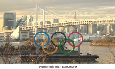 TOKYO, JAPAN - FEB 2020 : The Five Ring Symbol Of The Olympic Games In Front Of Odaiba Rainbow Bridge. Japan Will Host The Tokyo 2020 Summer Olympic And Paralympic. Shot In Sunset Time.