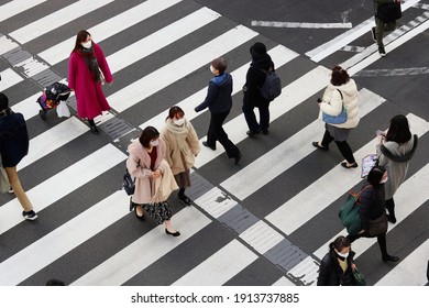 TOKYO, JAPAN - February 10, 2021: Overhead View Of People Using A Crosswalk In Tokyo's Iidabashi Area. Some Motion Blur.