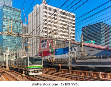 Tokyo, Japan - February 16 2021: Tokyo Sports Square Building Promoting The Tokyo 2020 Olympic And Paralympic Games Along The Tracks Of The JR Yurakucho Station With A E231-1000 Series Suburban Train.