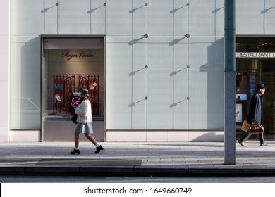 TOKYO, JAPAN -  February 19, 2020: View Of A Ginza Street With Pedestrians In The Sunlight And Shade Passing Matsuya Department Store Which Has A Roger Vivier Window Display. 