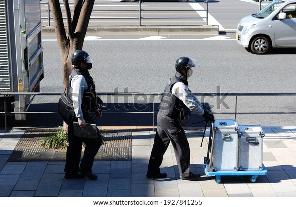 TOKYO, JAPAN - February 19,\
2021: A pair of Alsok security guards at work in Tokyo\'s Omotesando\
area.