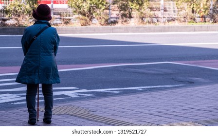 TOKYO, JAPAN - FEBRUARY 21ST, 2019. Elderly Woman Waiting For A Bus At A Shibuya Bus Stop During Winter Season.