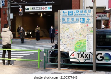 TOKYO, JAPAN - February 25, 2022: Street In Tokyo's Shinjuku Area With A Street Map, Taxi, Crosswalk And A Subway Station Entrance.