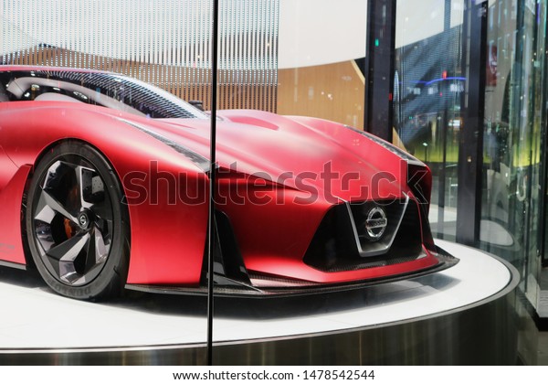 TOKYO, JAPAN - July 12, 2019: A Nissan Concept\
2020 Vision Gran Turismo on a revolving platform in Ginza Place\
Nissan Crossing showroom with the lights of nearby buildings\
reflected in the window.