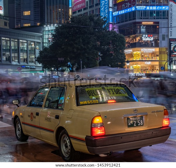 TOKYO, JAPAN\
- JULY 14TH, 2019. Yellow taxi in the street of Shibuya on a rainy\
night. Selective focus, long\
exposure.