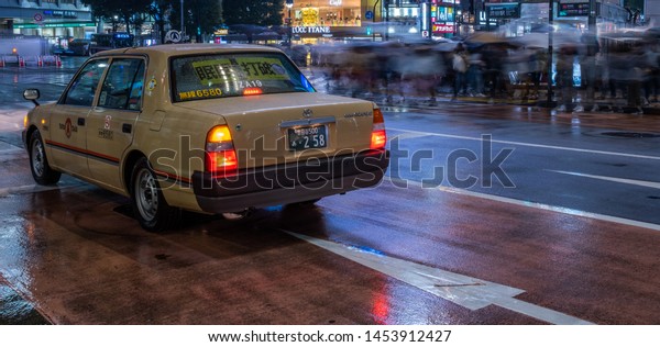 TOKYO, JAPAN\
- JULY 14TH, 2019. Yellow taxi in the street of Shibuya on a rainy\
night. Selective focus, long\
exposure.