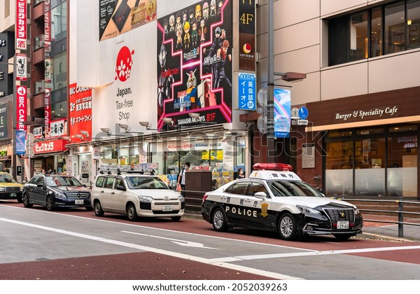 tokyo, japan - july 20 2021: Japanese police car\
with emergency beacons lights in stand by at the head of a traffic\
line in the tourist district of Ikebukuro with tax-free shops and\
anime stores.