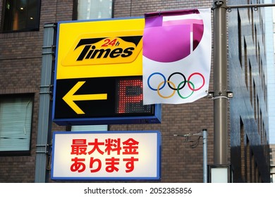 
TOKYO, JAPAN - July 28, 2021: A Tokyo Olympic Flag On A Lamppost By A Times Car Park Sign In Tokyo's Otemachi Area. 