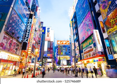 Tokyo, Japan - July 29, 2015: Bright neon lights and billboard advertisements on building sides in busy Akihabara electronics hub during dusk blue hour on a summer night in downtown. Horizontal