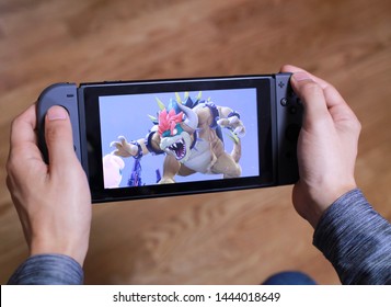 Tokyo, Japan - July 7, 2019 - Man Holding A Black Nintendo Switch Playing Super Smash Brothers With Flooring In The Background