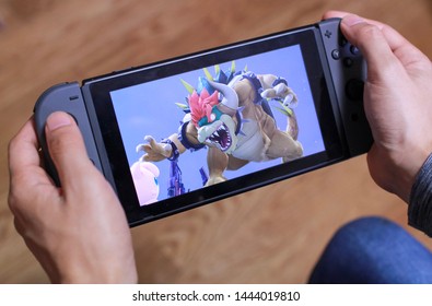 Tokyo, Japan - July 7, 2019 - Man Holding A Black Nintendo Switch Playing Super Smash Brothers With Flooring In The Background