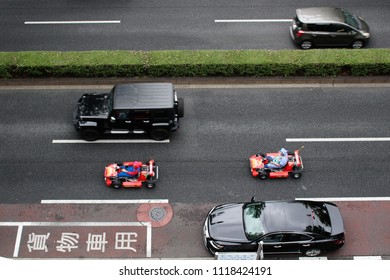 TOKYO, JAPAN - June 16, 2018: Overhead View Of Road In Omotesando On Which A Pair Of Rental Maricar Go-carts Are Being Driven. The Go-carts Are Moving So There Is Some Motion Blur In The Photograph.