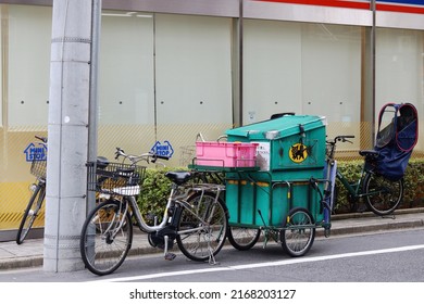 TOKYO, JAPAN - June 16, 2022: A Yamato Transport Company electric bicycle and cart parked outside a convenience store in Tokyo's Taito Ward.