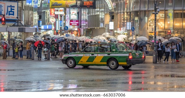 TOKYO,\
JAPAN - JUNE 18TH 2017. Taxi at the famous Shibuya crossing during\
a rainy night. The rainy season, locally known as tsuyu or baiyu,\
begins the from June until mid July in\
Japan.