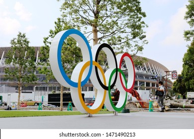 TOKYO, JAPAN - June 21, 2019: Olympic Rings Monument At Tokyo Sport Olympic Square, The Headquarters Of JSPO & JOC. Opposite Is  The Under-construction National Stadium Being Built For 2020 Olympics.