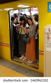 TOKYO, JAPAN - June 28, 2019: People Using Smart Phones On A Crowded Ginza Line Subway Train About To Depart From The Platform Of Nihombashi Metro Station.