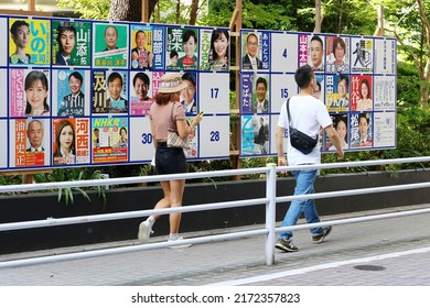 TOKYO, JAPAN - June 28, 2022: People Walk Past An Official Noticeboard On A Street In Tokyo's Ginza Area With Posters Of Candidates Standing In The House Of Councillors. Some Motion Blur.