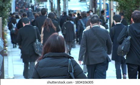 TOKYO, JAPAN - MAR 2020 : Back Shot Of Unidentified Crowd Of People Walking Down The Street In Busy Rush Hour. Many Commuters Going To Work. Japanese Business Man And Woman, Job And Lifestyle Concept.