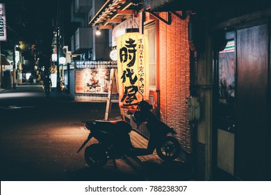 Tokyo, Japan - March 2017: Tokyo Night Street Scene Of A Quiet Alleyway With Motorcycle And Moody Red Lantern 