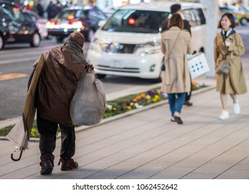 TOKYO, JAPAN - MARCH 29TH, 2018. Homeless Old Man Walking In The Street Of Ginza At Night.