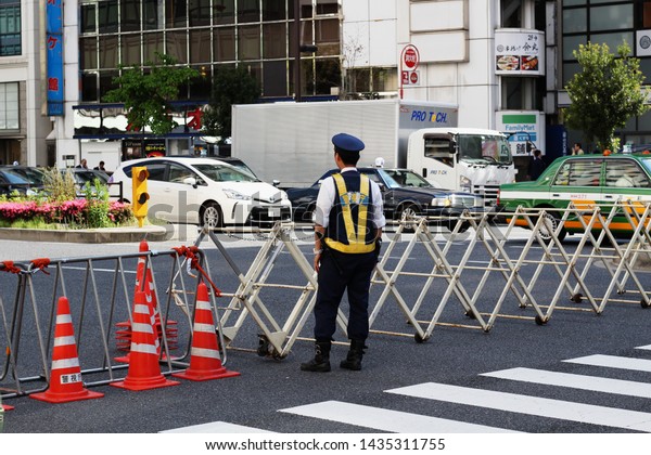 TOKYO, JAPAN - May 17, 2019: A police officer mans\
a temporary barrier across a road while traffic light is red in\
Akasaka. It is training exercise for the following weekend\'s\
President Trump visit.