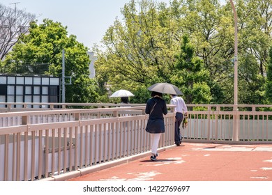 Tokyo, Japan - May 23, 2019: A Woman Crosses The Famous Harajuku Bridge In Harajuku, Shibuya, Carrying An Umbrella As A Parasol For Sun Protection, A Practice Commonly Followed In The City.